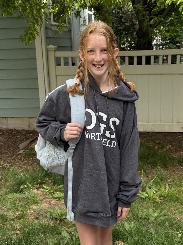 Delila in a grey hoodie with braids and her backpack