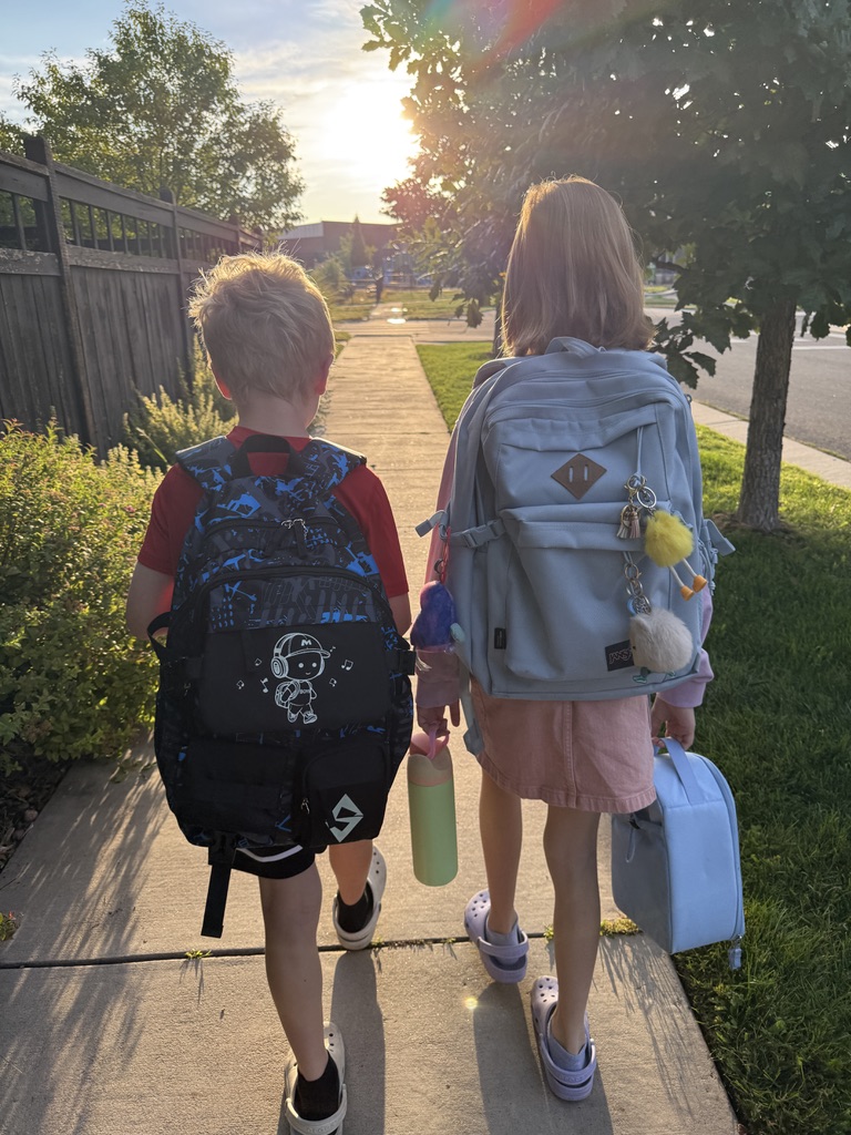 Jackson and Delila walking together into the sunrise, backpacks on